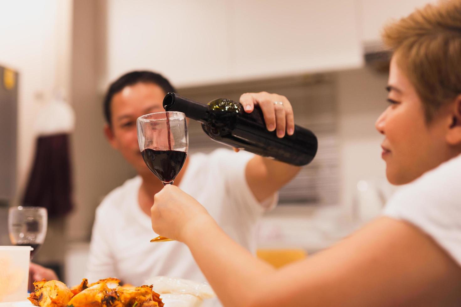 mari verser rouge du vin dans le sien épouse verre pendant dîner à maison. photo