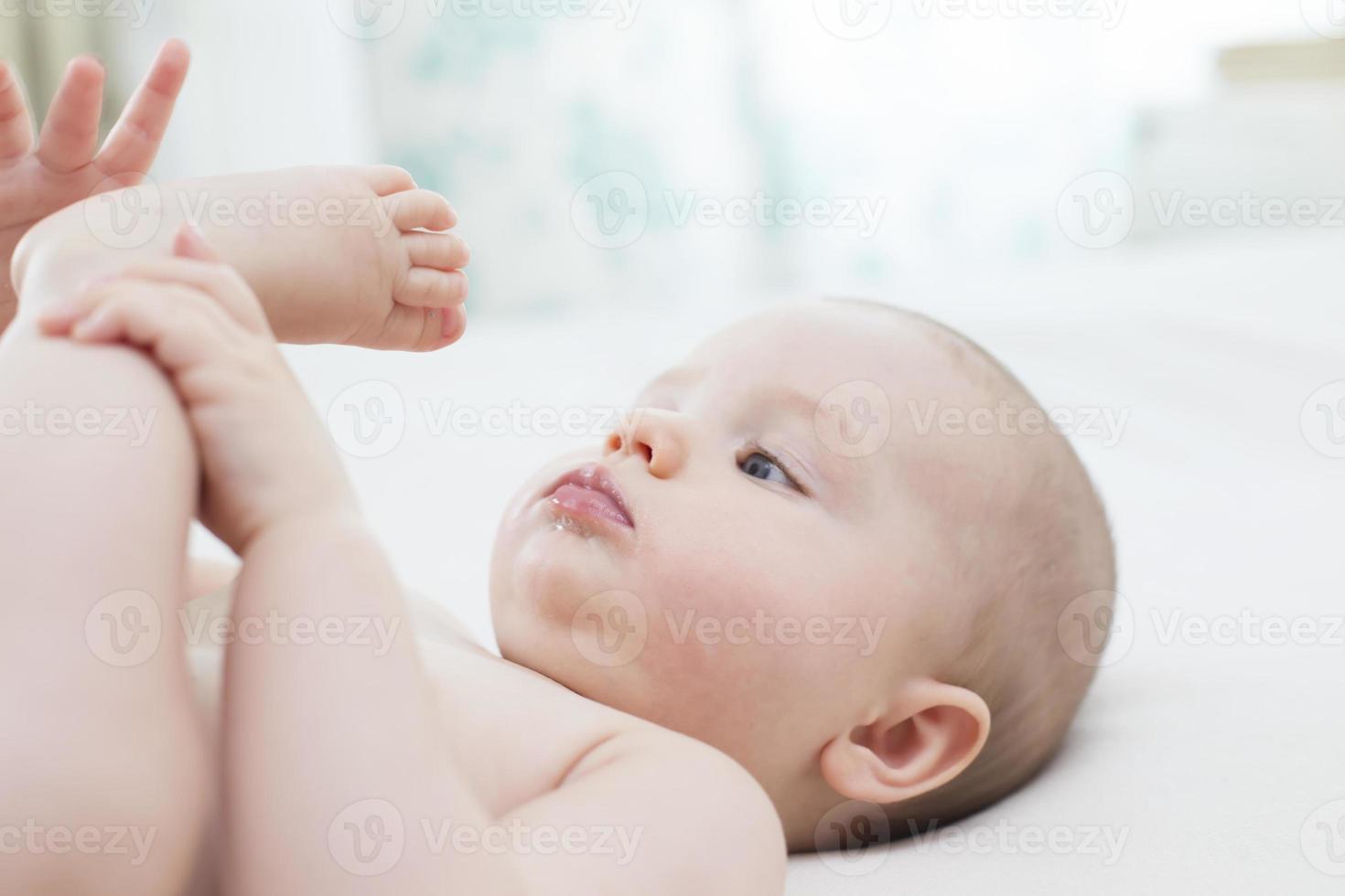 petite fille couchée et tirant sa jambe dans sa bouche photo