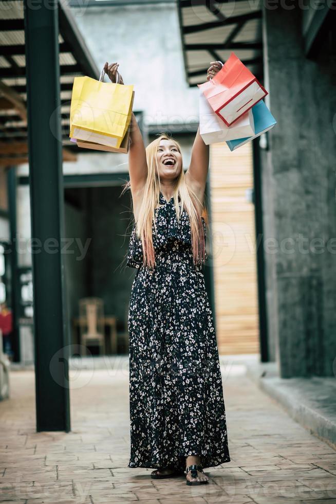 Portrait d'une jeune femme heureuse avec des sacs à provisions marchant dans la rue photo