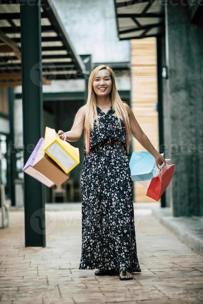 Portrait d'une jeune femme heureuse avec des sacs à provisions marchant dans la rue photo