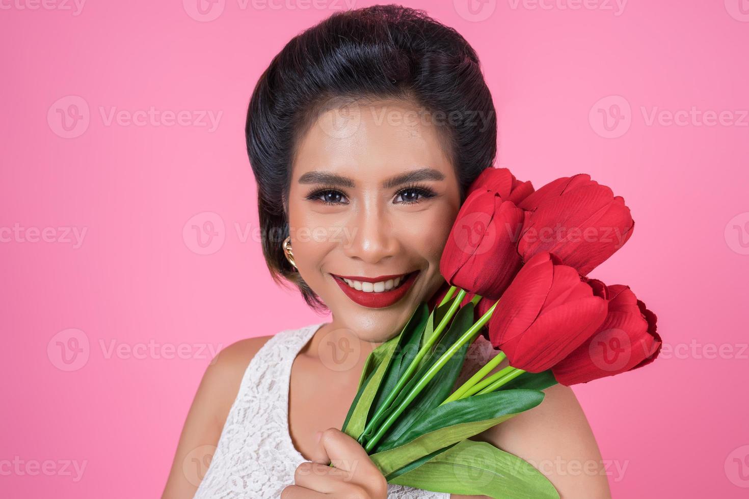 Portrait d'une belle femme avec bouquet de fleurs de tulipes rouges photo