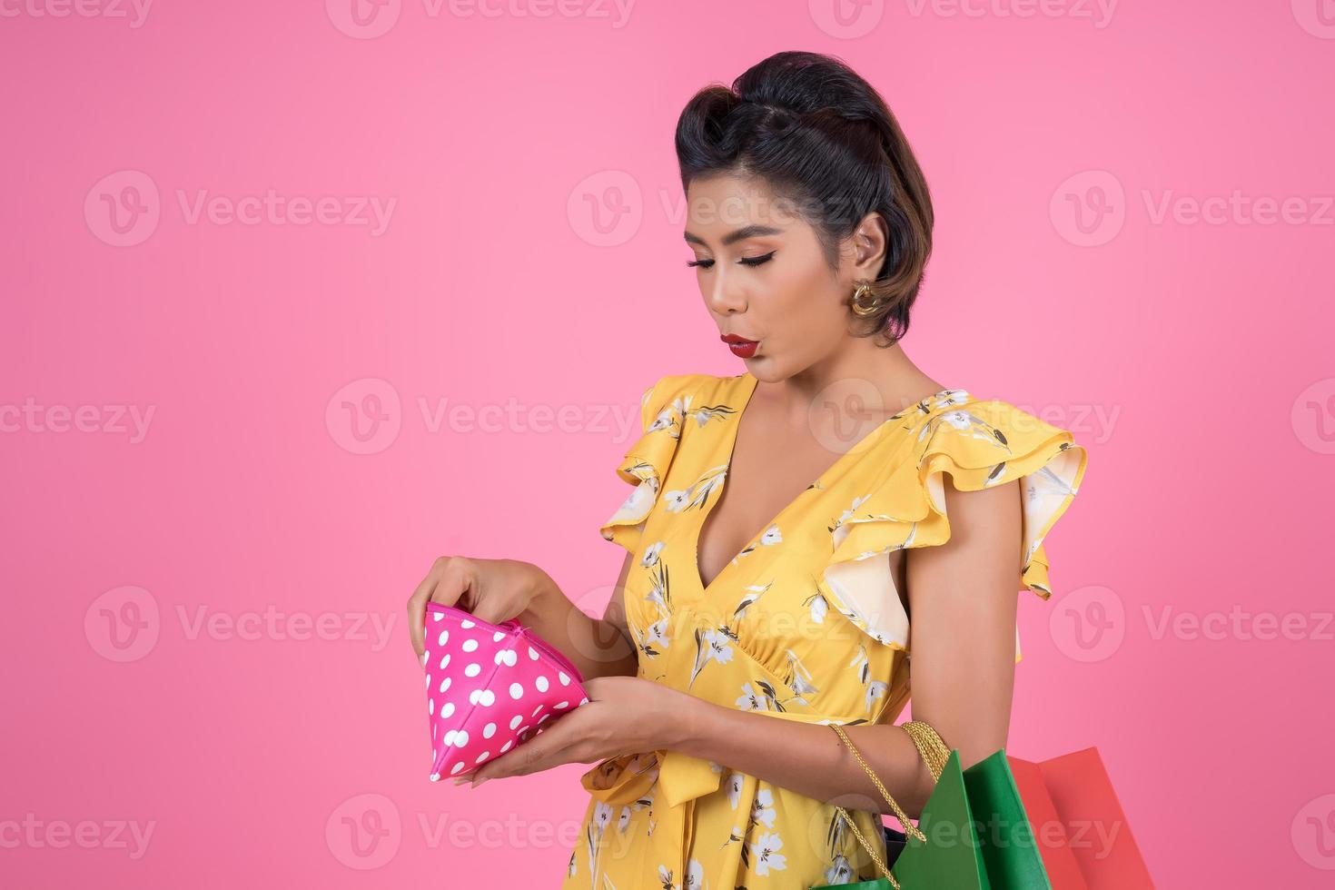 jeune femme à la mode tenant un portefeuille avec de l'argent et des sacs à provisions photo