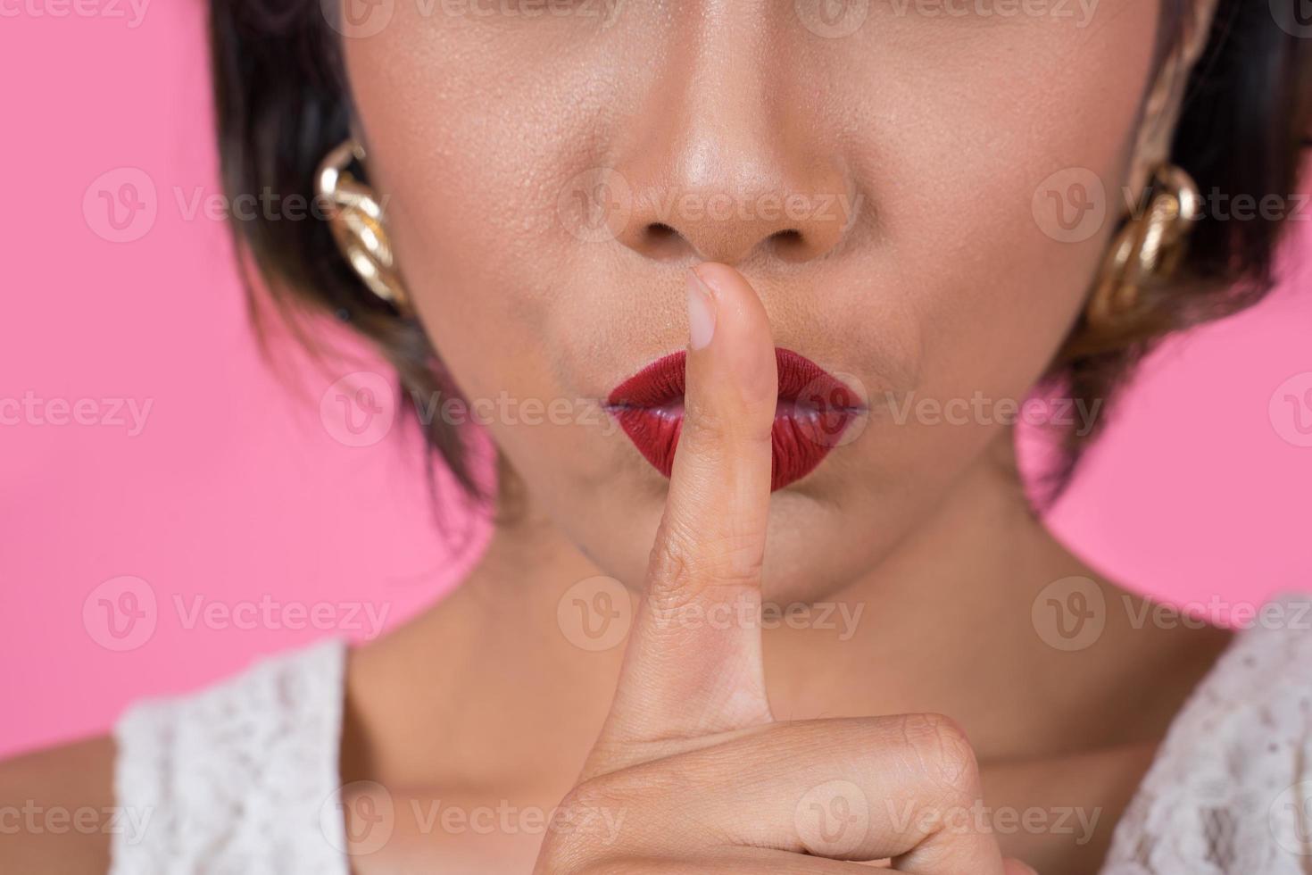 belle femme asiatique avec des lèvres rouges montrant signe silence silence photo