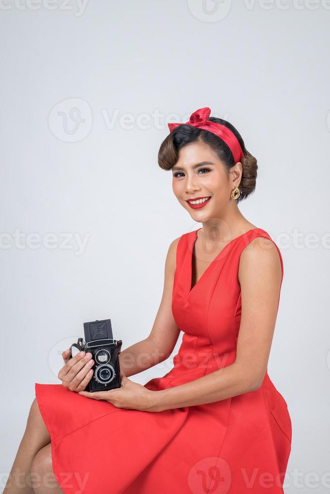 Photographe femme à la mode heureuse tenant un appareil photo vintage rétro