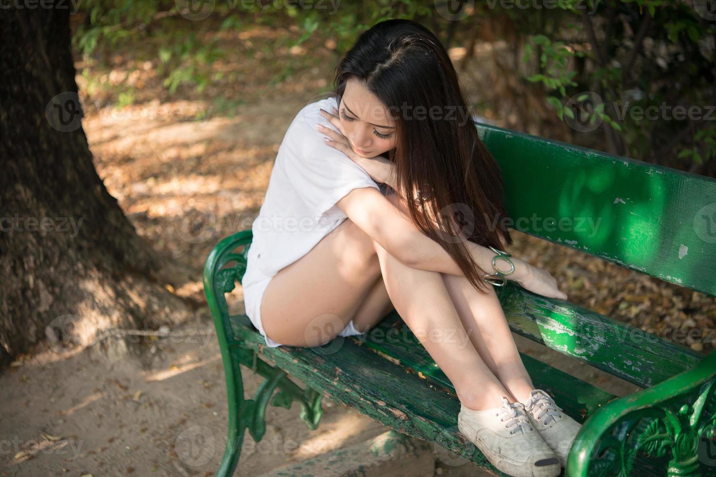 Triste femme seule assise sur un banc seul dans le parc photo