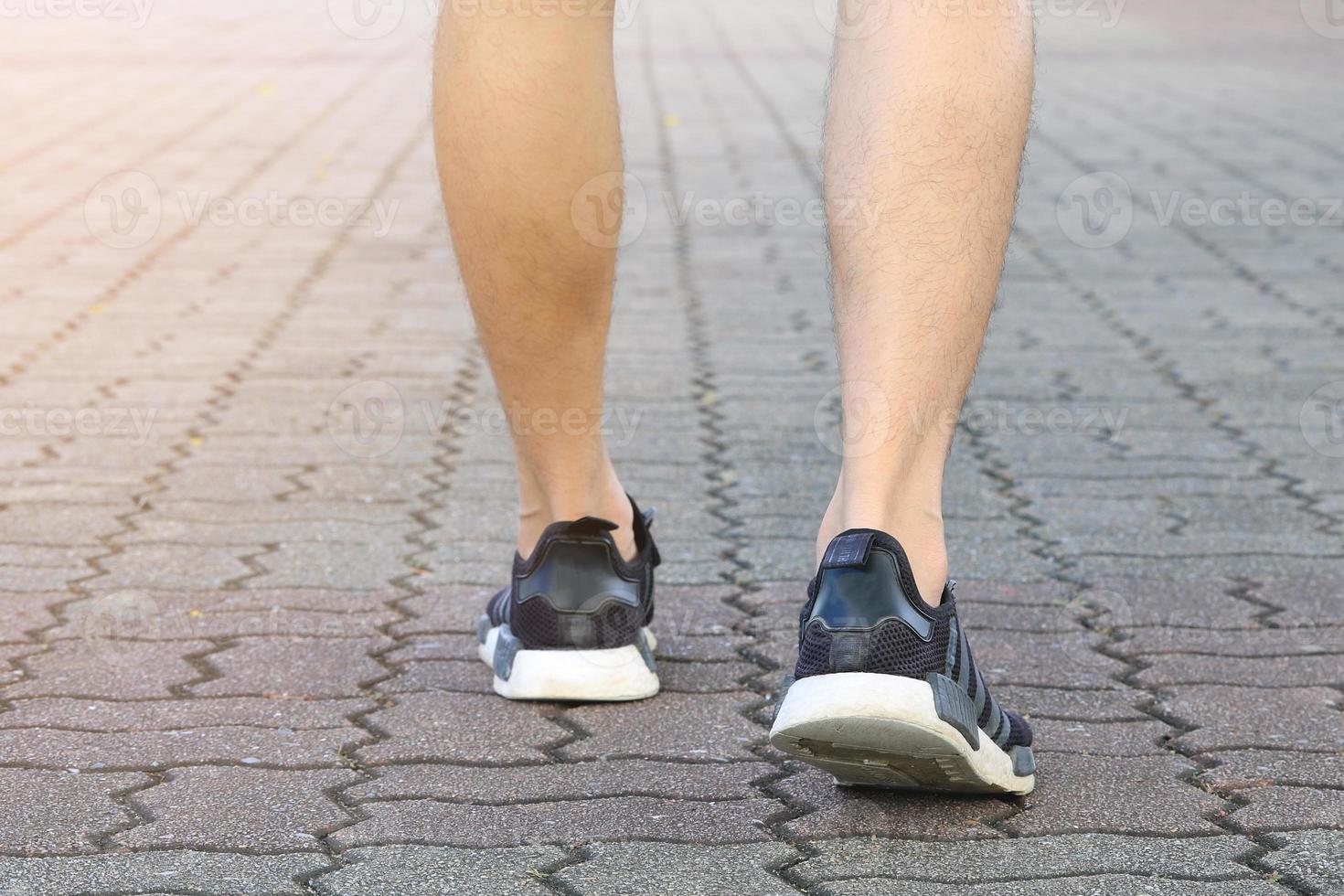 Les jambes de l'homme avec des chaussures de tennis sur la surface de la brique photo