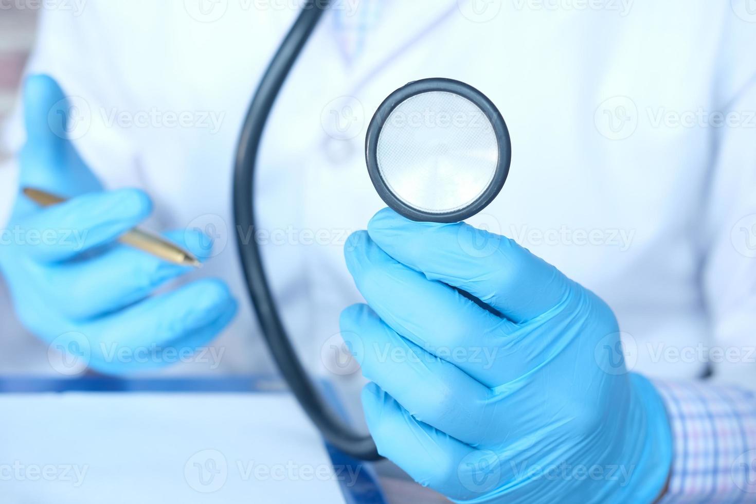 La main du médecin dans des gants de protection tenant un stéthoscope photo