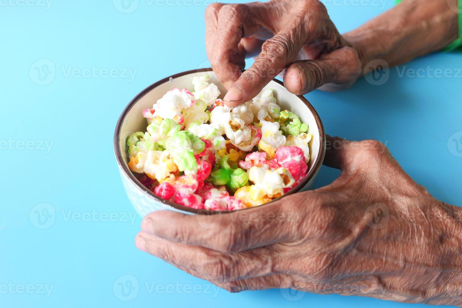 mains de femme senior tenant un bol de pop-corn coloré photo