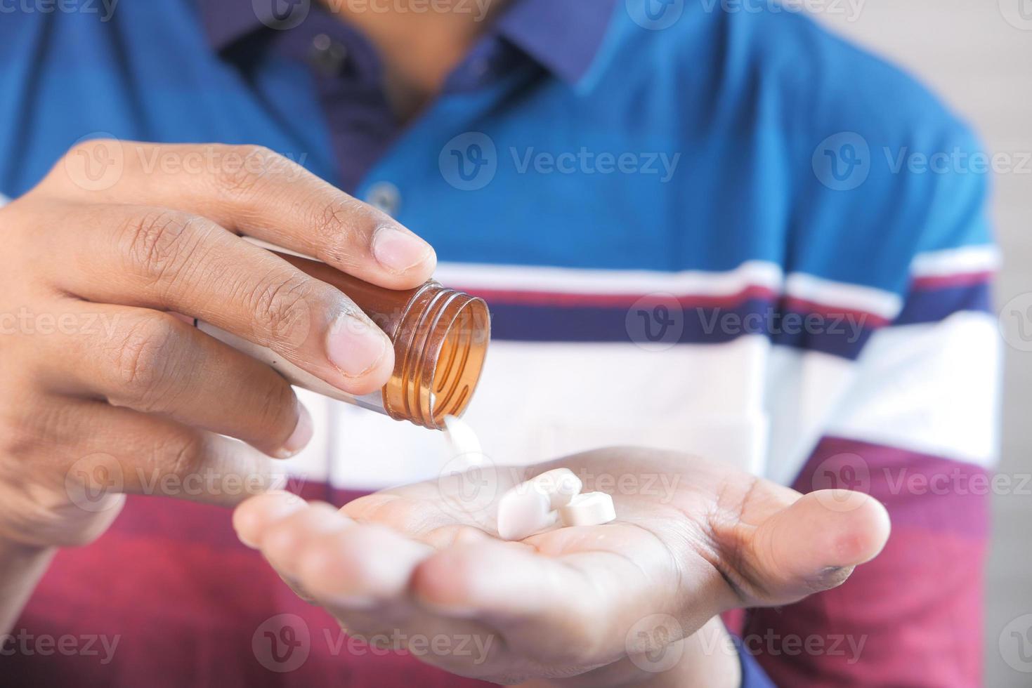 La main de l'homme avec un médicament renversé du contenant de la pilule photo