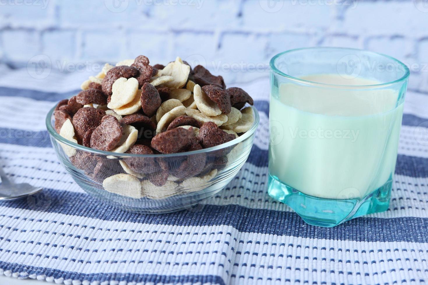 Flocons de maïs au chocolat dans un bol et lait sur table photo