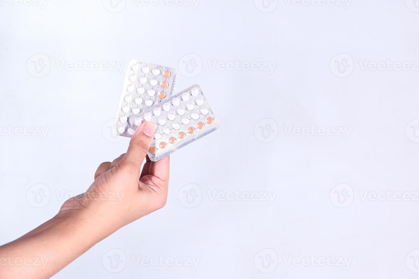 Woman's hand holding pilules contraceptives isolé sur fond blanc photo