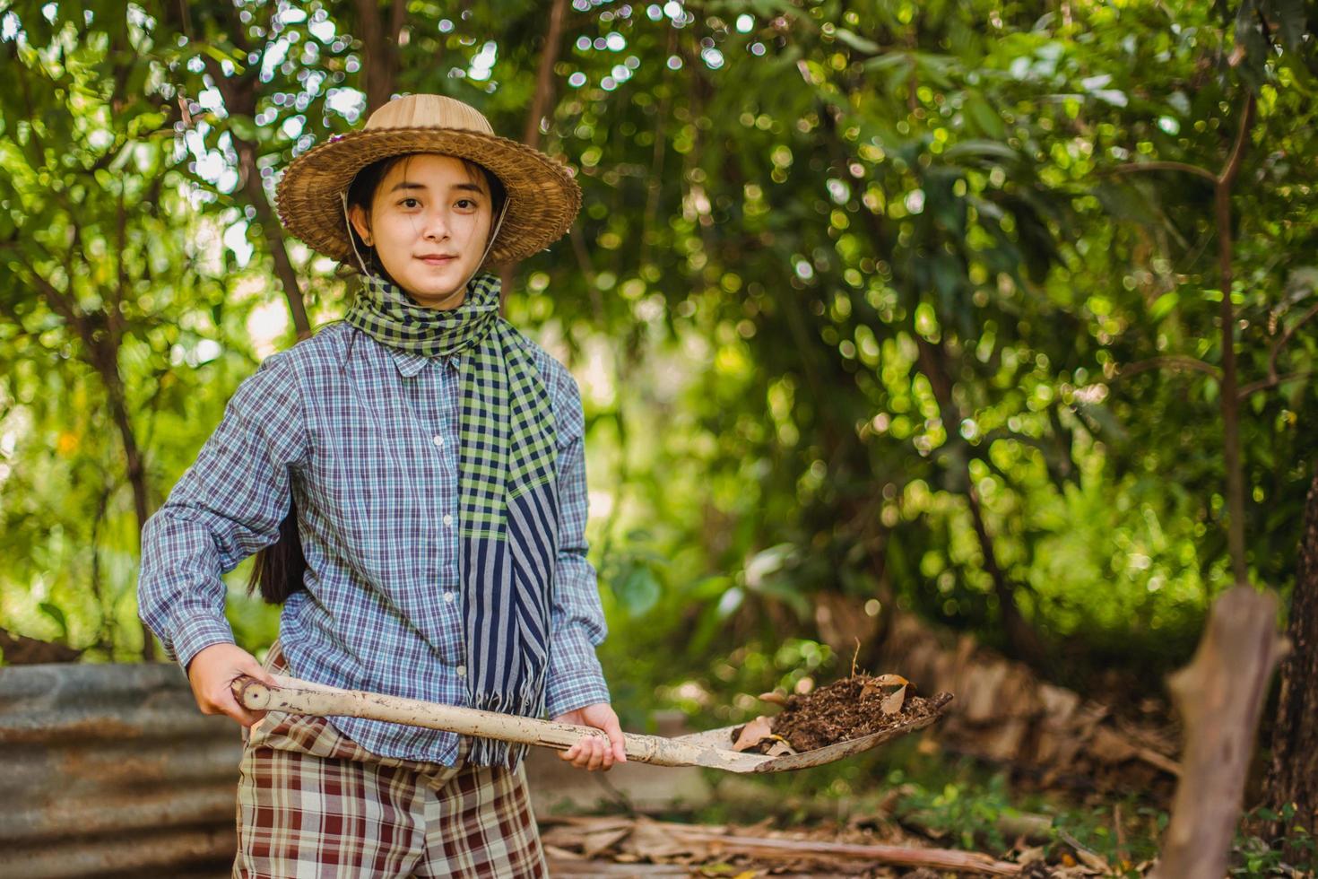 Jeune jolie agriculteur femme permanent sur les terres agricoles et inspecter agricole cultures photo