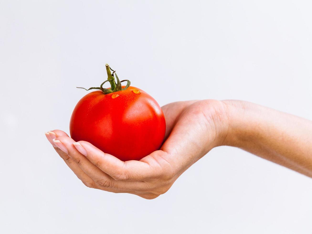 main tenant une tomate juteuse photo