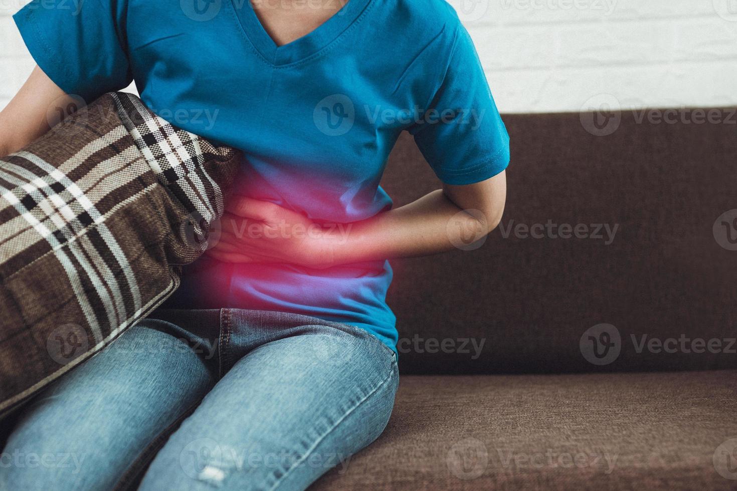 Femme ayant des douleurs à l'estomac sur le canapé photo