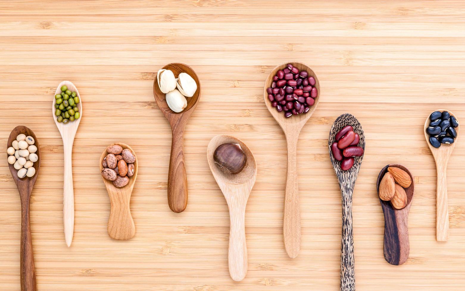 Assortiment de haricots et lentilles dans des cuillères en bois sur bois photo