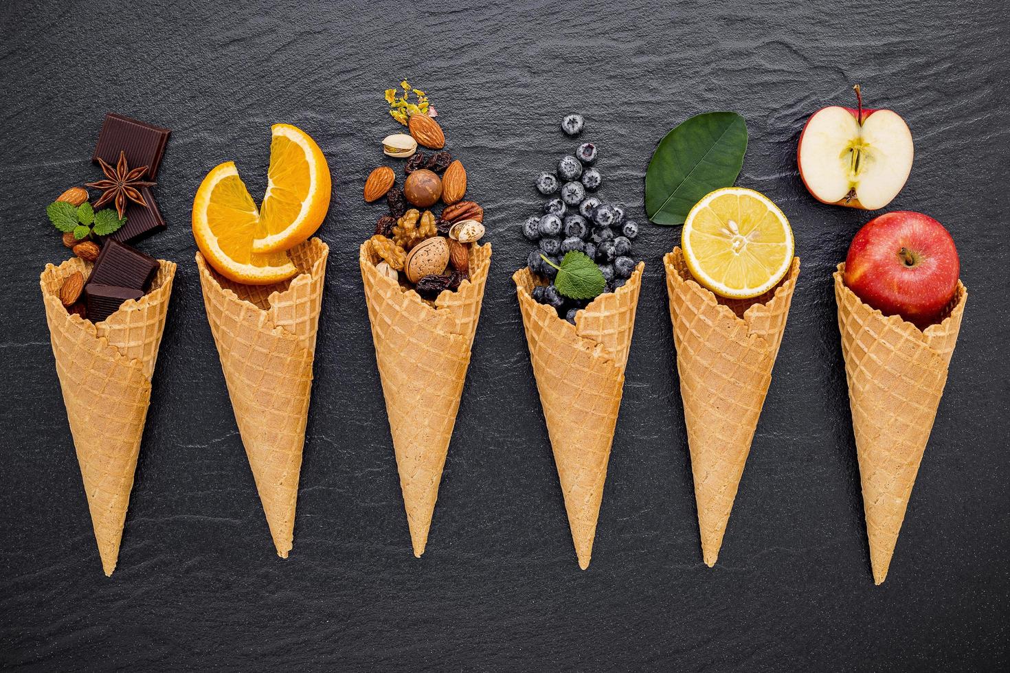 Fruits, noix et chocolat avec des cornets de crème glacée sur fond sombre photo