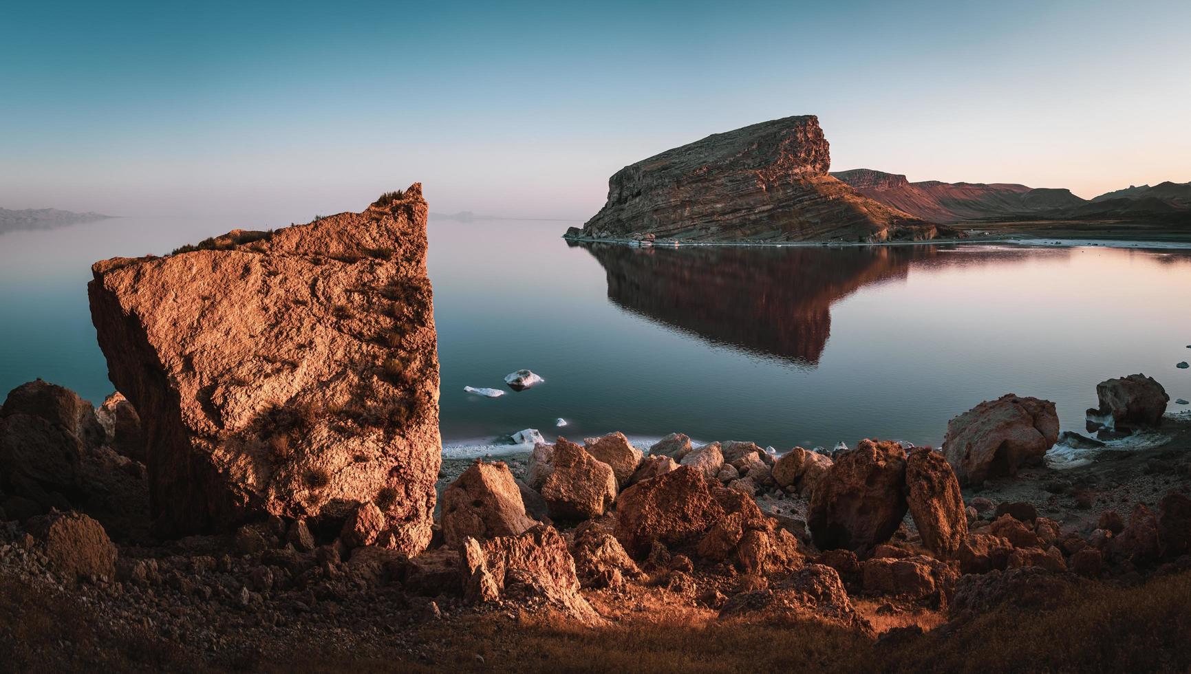 De gros rochers au lac Urmia avec des montagnes et un ciel bleu clair en Iran photo