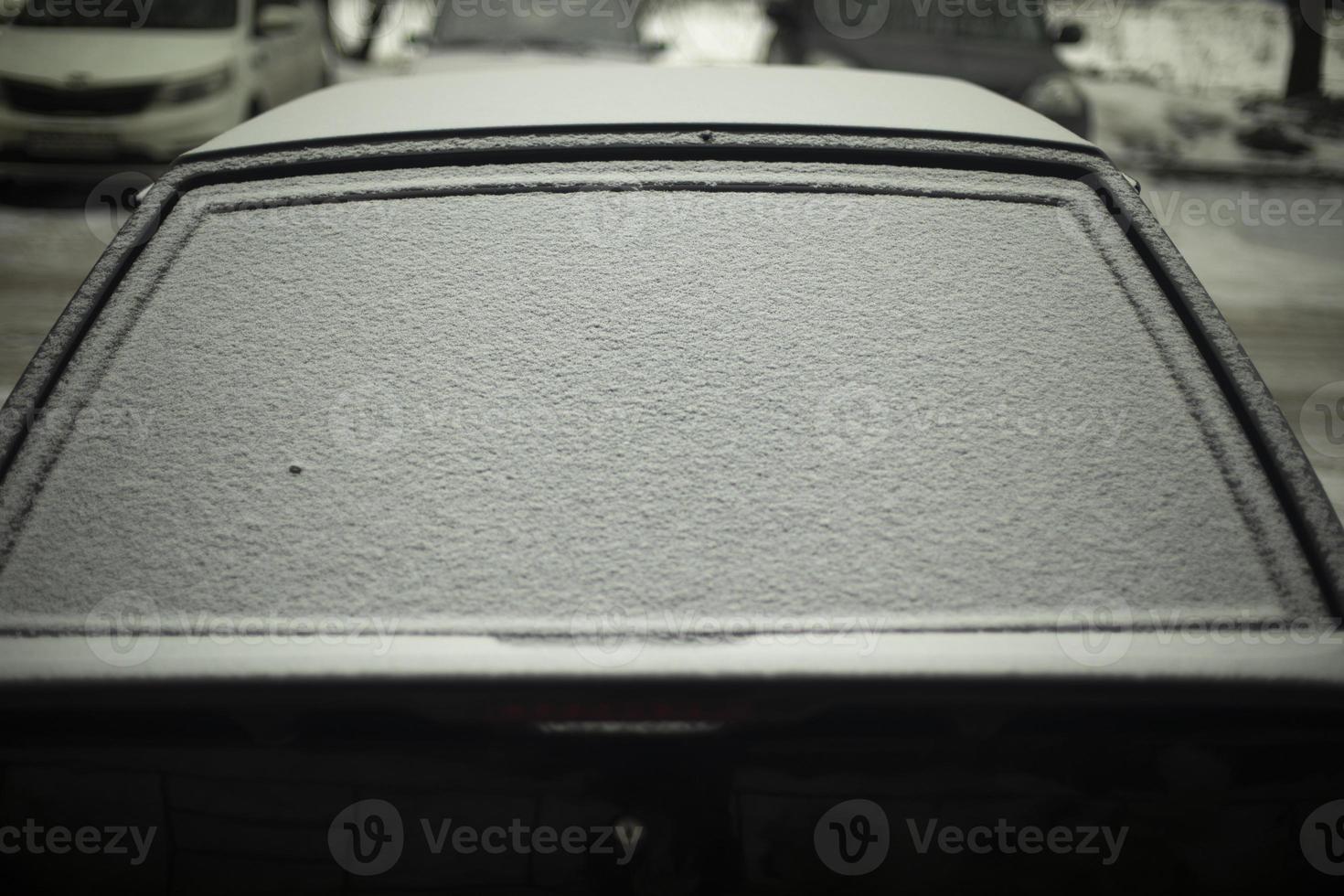 arrière fenêtre de voiture dans neige. neige par auto. voiture est garé dans l'hiver. photo