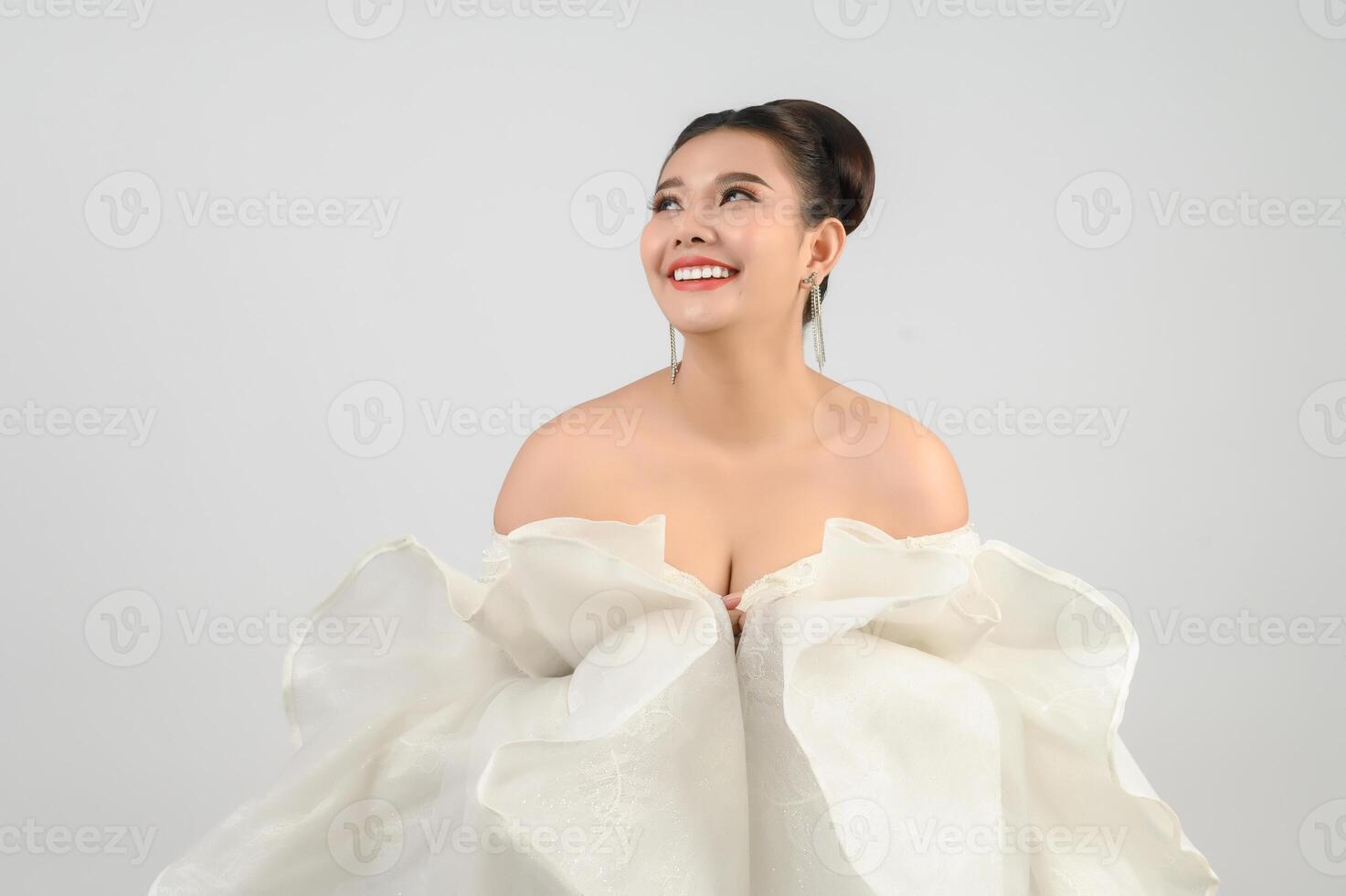 Jeune belle mariée asiatique souriante avec plaisir sur fond blanc photo