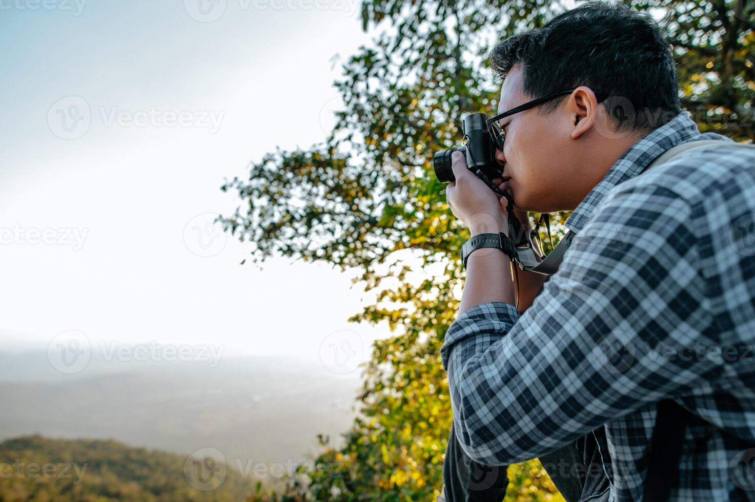 un jeune routard utilise un appareil photo pour prendre des photos en forêt.