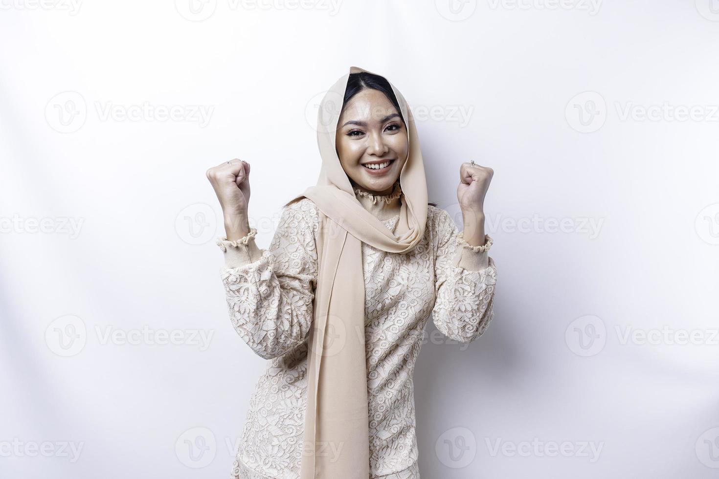 Une jeune femme musulmane asiatique avec une expression réussie heureuse portant un hijab isolé par fond blanc photo