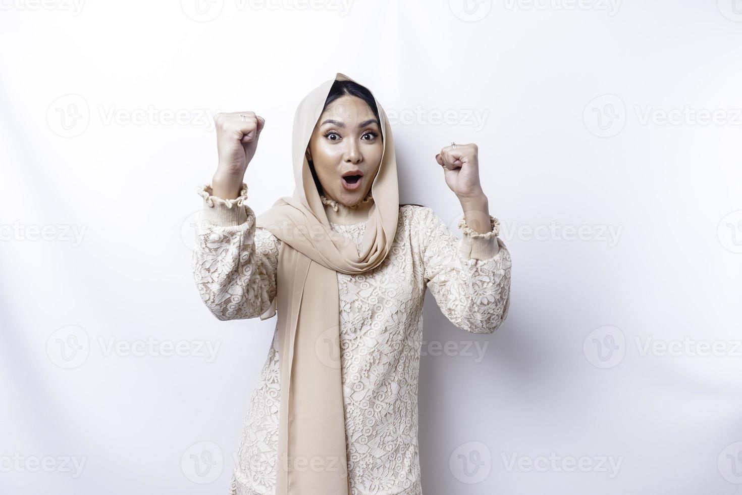 Une jeune femme musulmane asiatique avec une expression réussie heureuse portant un hijab isolé par fond blanc photo