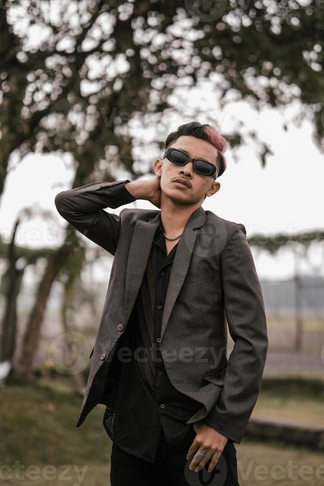 un asiatique homme avec des lunettes de soleil posant dans une gris costume dans le Cour photo