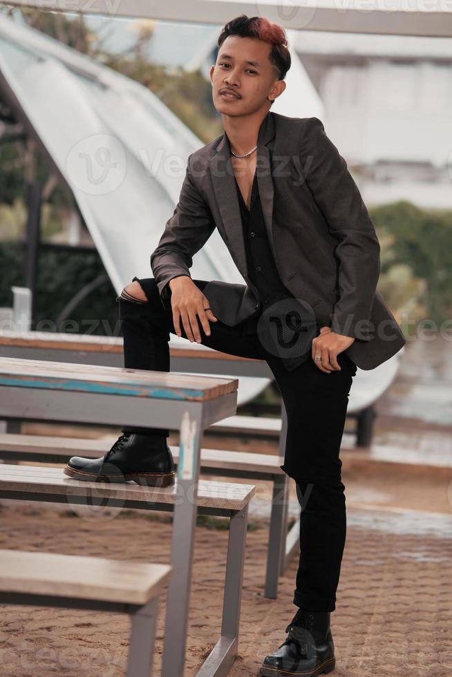 une grandi homme dans une gris costume posant autour une café table dans une très viril et masculin manière avant entrer le Bureau photo