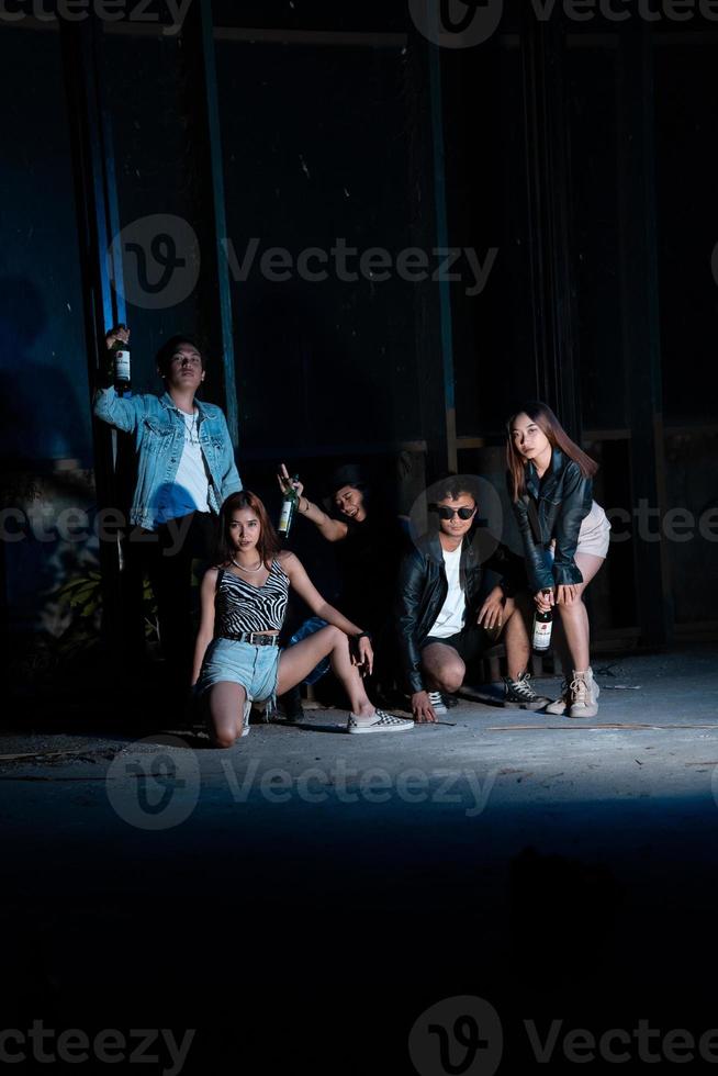 une groupe de adolescents dans excentrique vêtements posant ensemble comme copains dans une disco bar avec une très cool expression photo