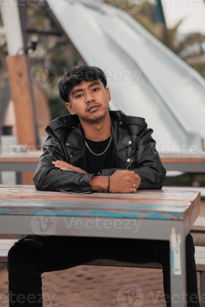 un asiatique homme avec une vilain visage portant une chaîne Collier et une noir cuir veste dans une café photo