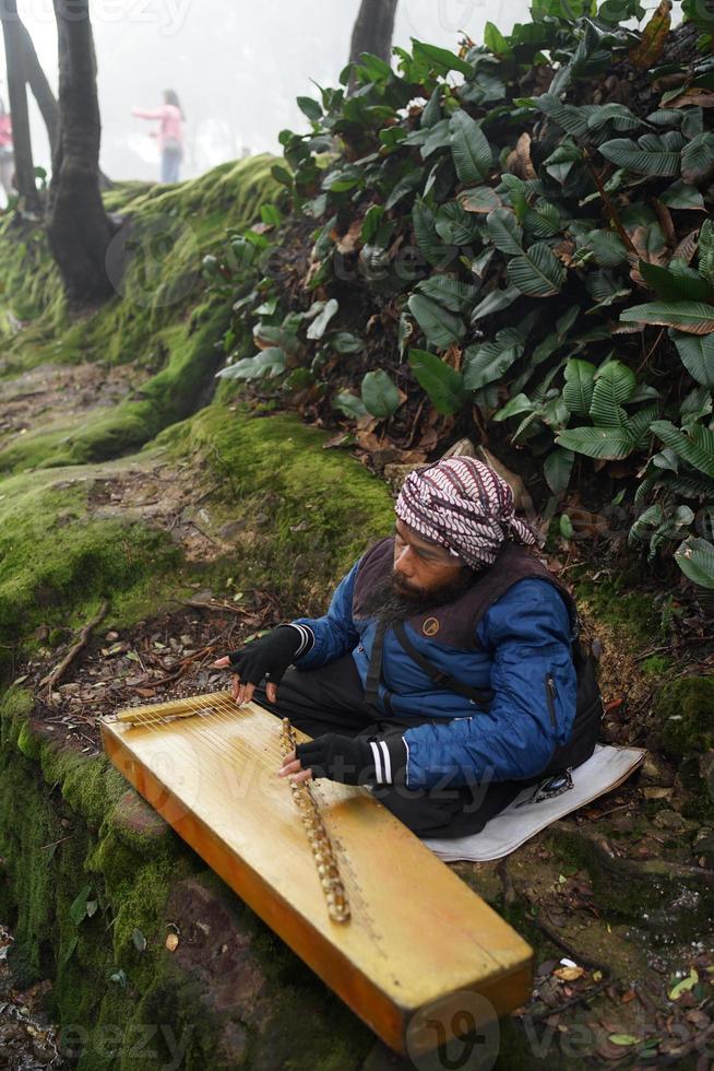 une homme en jouant kecapi traditionnel sundanais la musique dans le ciwidey, Bandung, ouest Java, Indonésie. photo