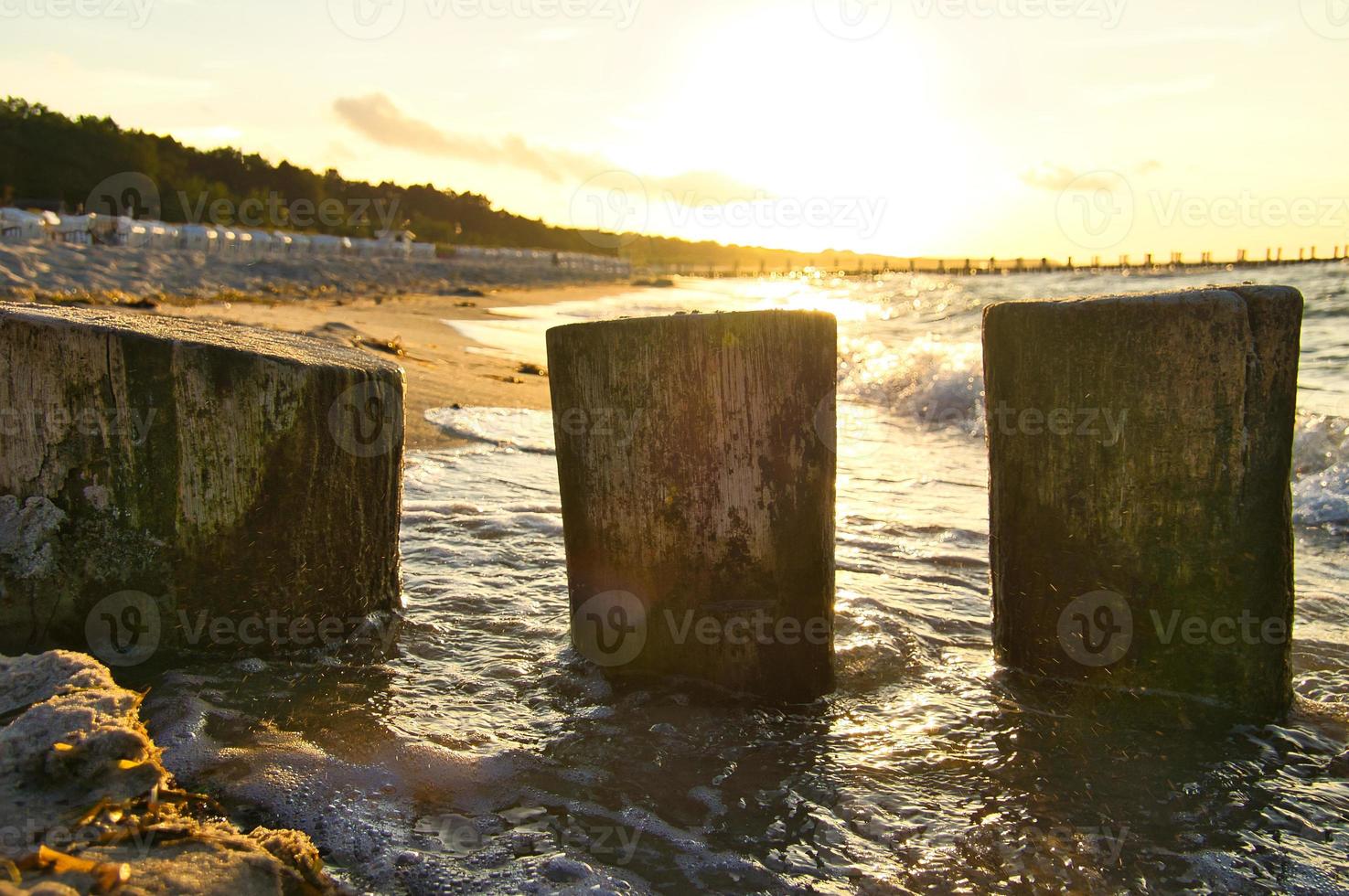 épis saillant dans le mer, à le coucher du soleil. plage avec des pierres dans le premier plan photo