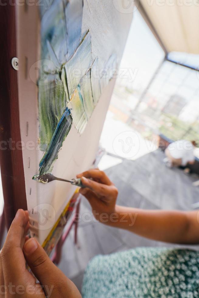 gros plan de la main d'une femme appliquant de la peinture sur une toile photo