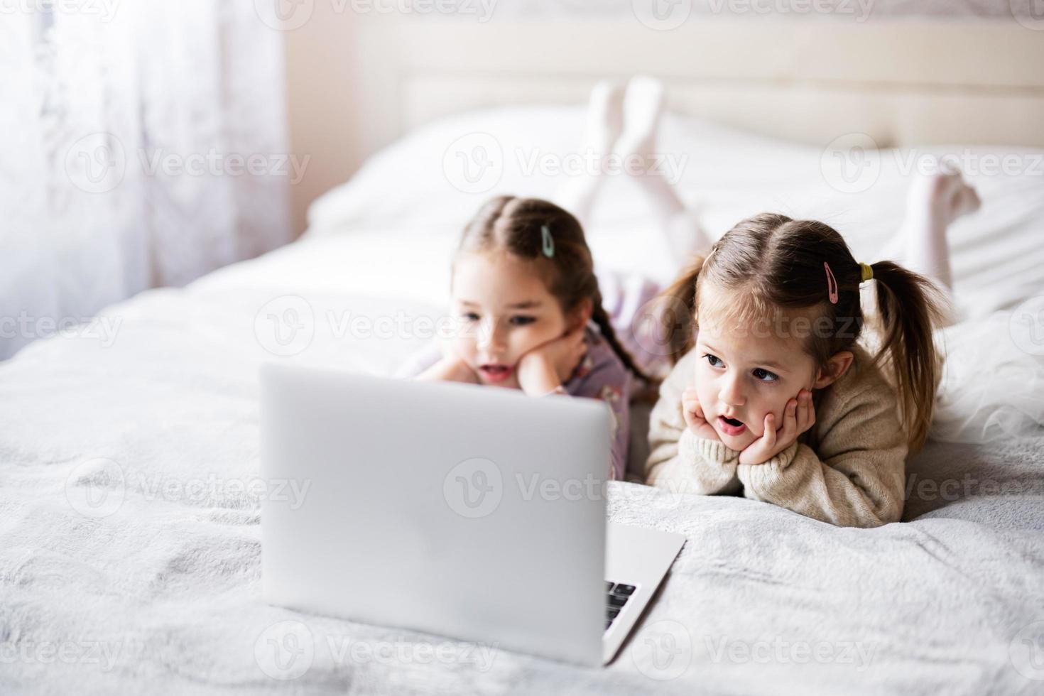 deux les filles sœurs en train de regarder sur portable. La technologie et Accueil concept. photo