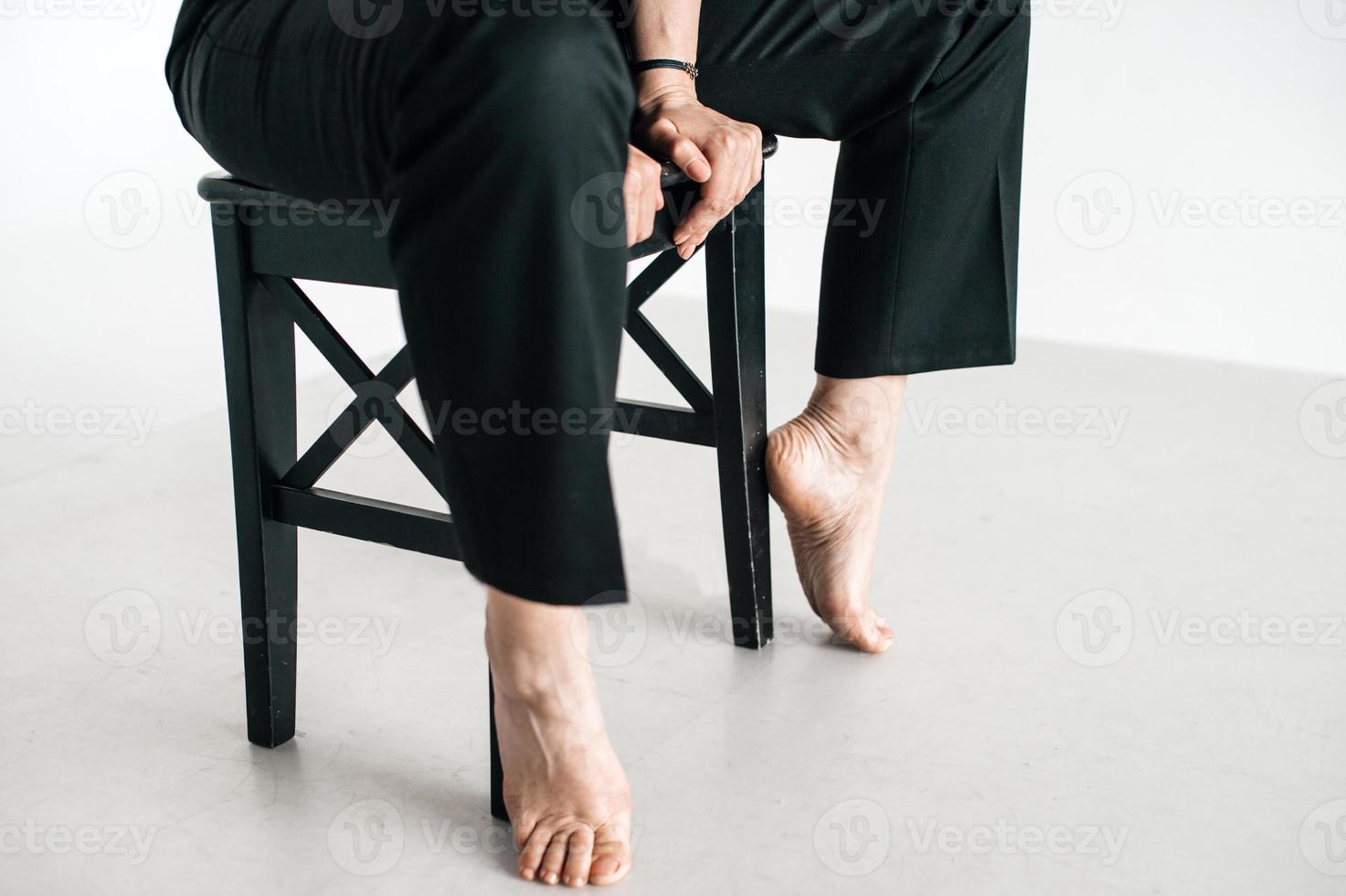 une homme est séance sur une chaise. le bras et jambes de une homme dans une noir costume. photo