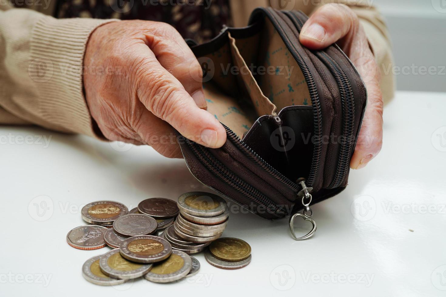 une femme âgée à la retraite comptant des pièces de monnaie et s'inquiète des dépenses mensuelles et du paiement des frais de traitement. photo