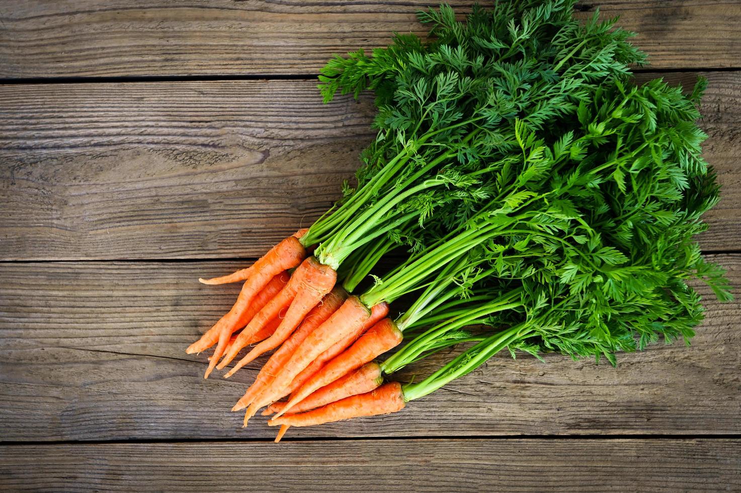 carotte sur fond de table en bois, carottes fraîches et sucrées pour la cuisson des aliments fruits et légumes pour le concept de santé, bouquet de carottes et feuille photo