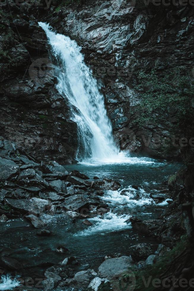 majestueux cascade entouré par des arbres dans le Alpes photo