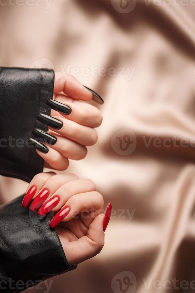 mains d'une jeune fille avec une manucure noire et rouge sur les ongles photo