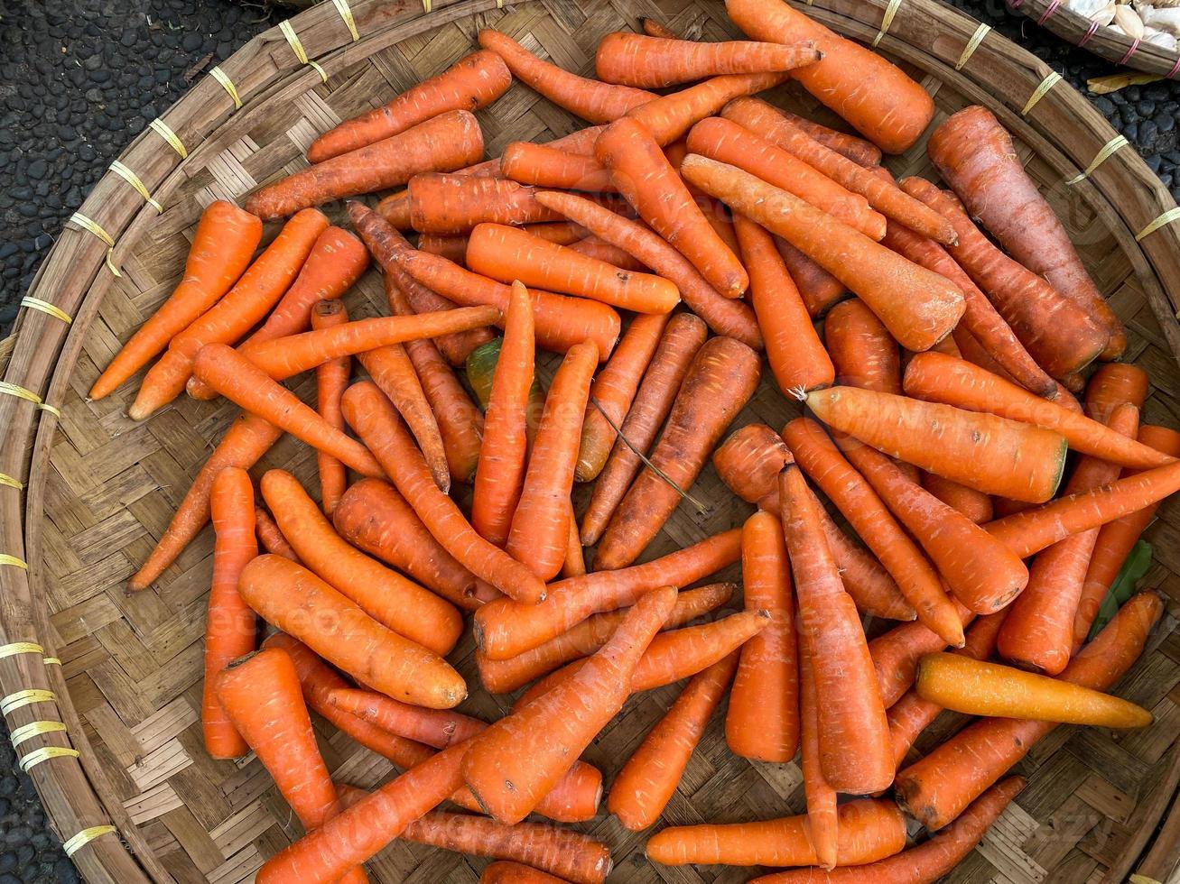 frais, biologique et imparfait carottes sur rond bambou plateau étant vendu à traditionnel marché photo