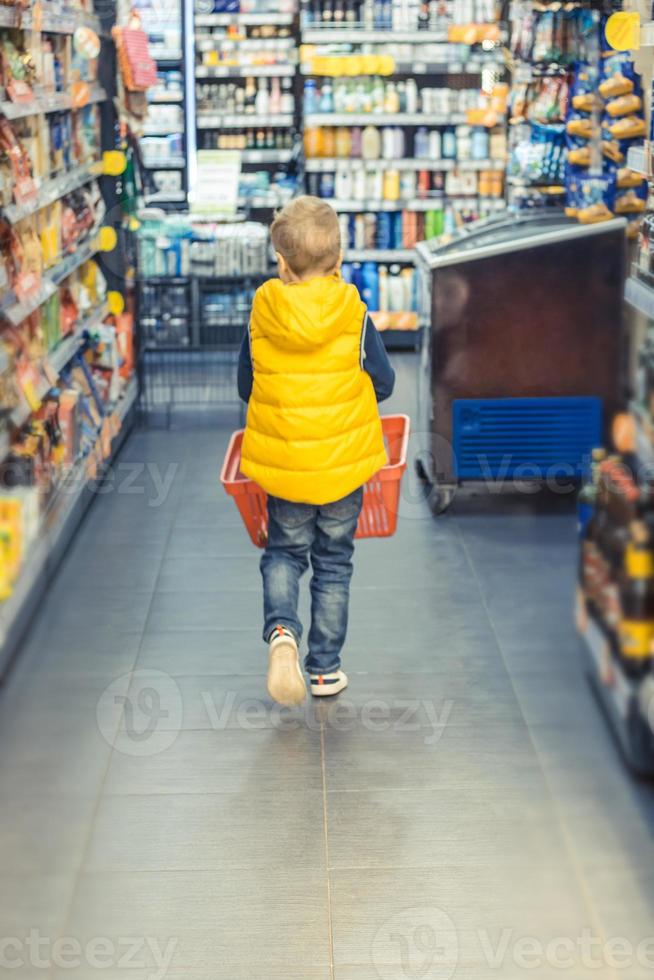 peu garçon achats dans supermarché. photo