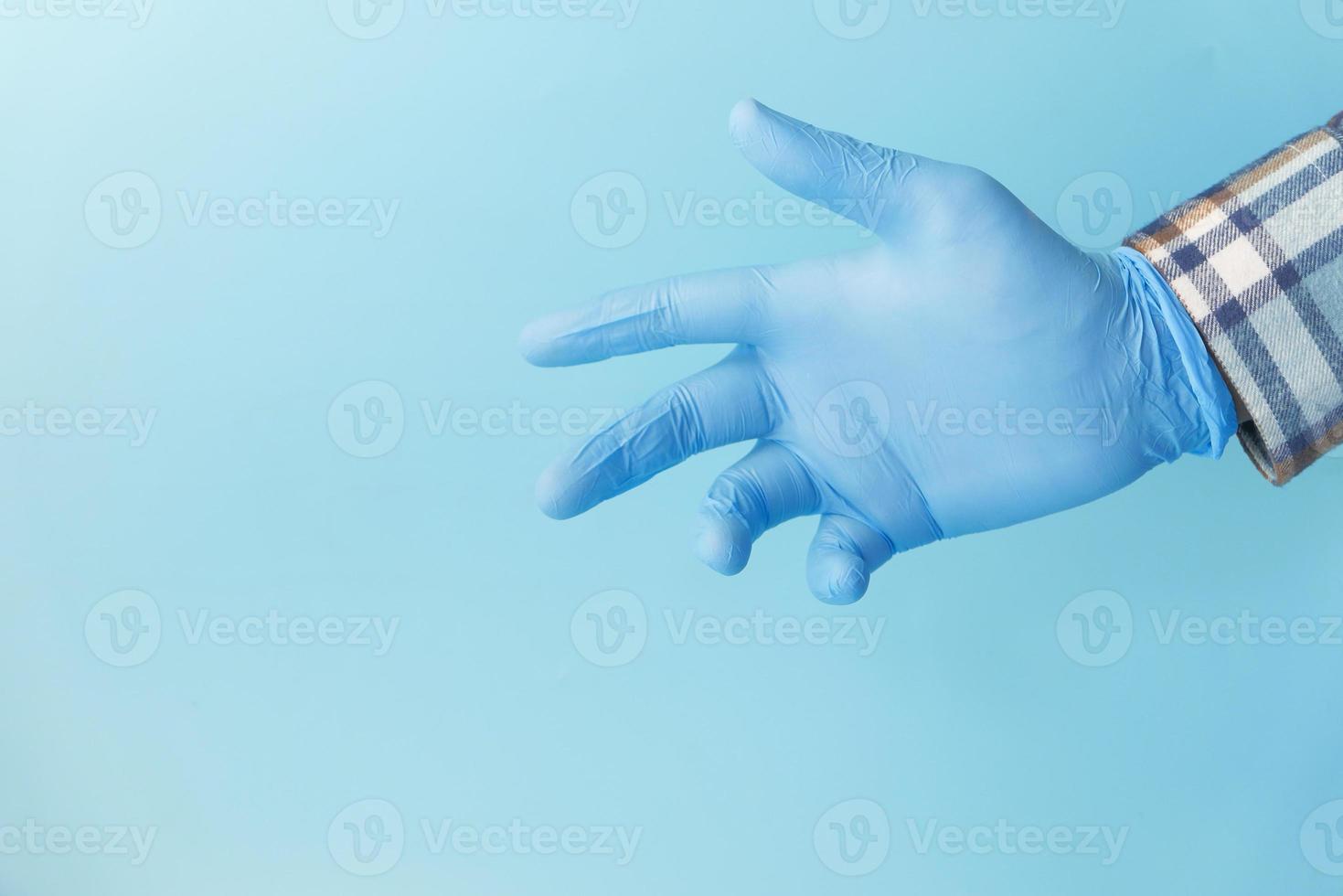 main du médecin avec un gant sur fond bleu photo