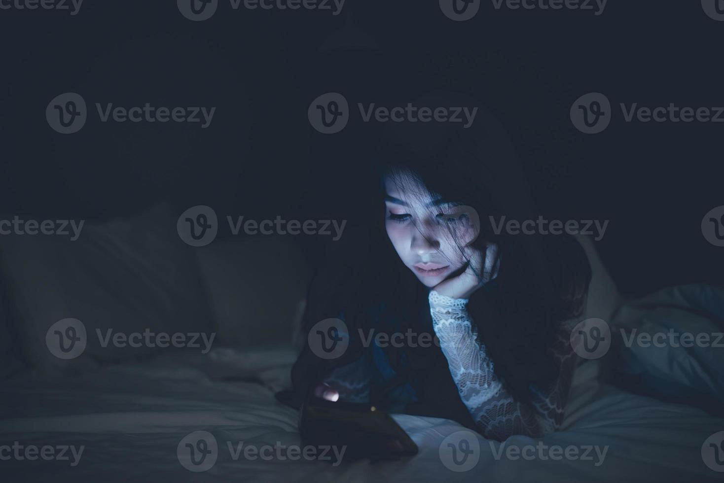 femme asiatique jouant au jeu sur smartphone dans le lit la nuit, thaïlande, toxicomane médias sociaux photo