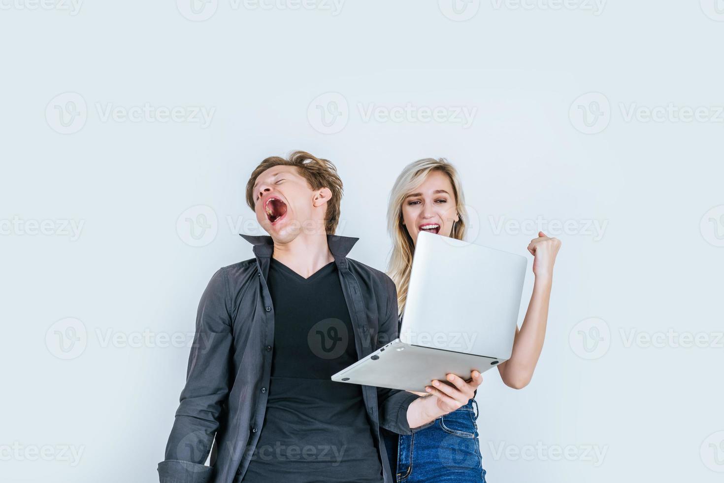 Portrait d'heureux jeune couple à l'aide d'un ordinateur portable en studio photo