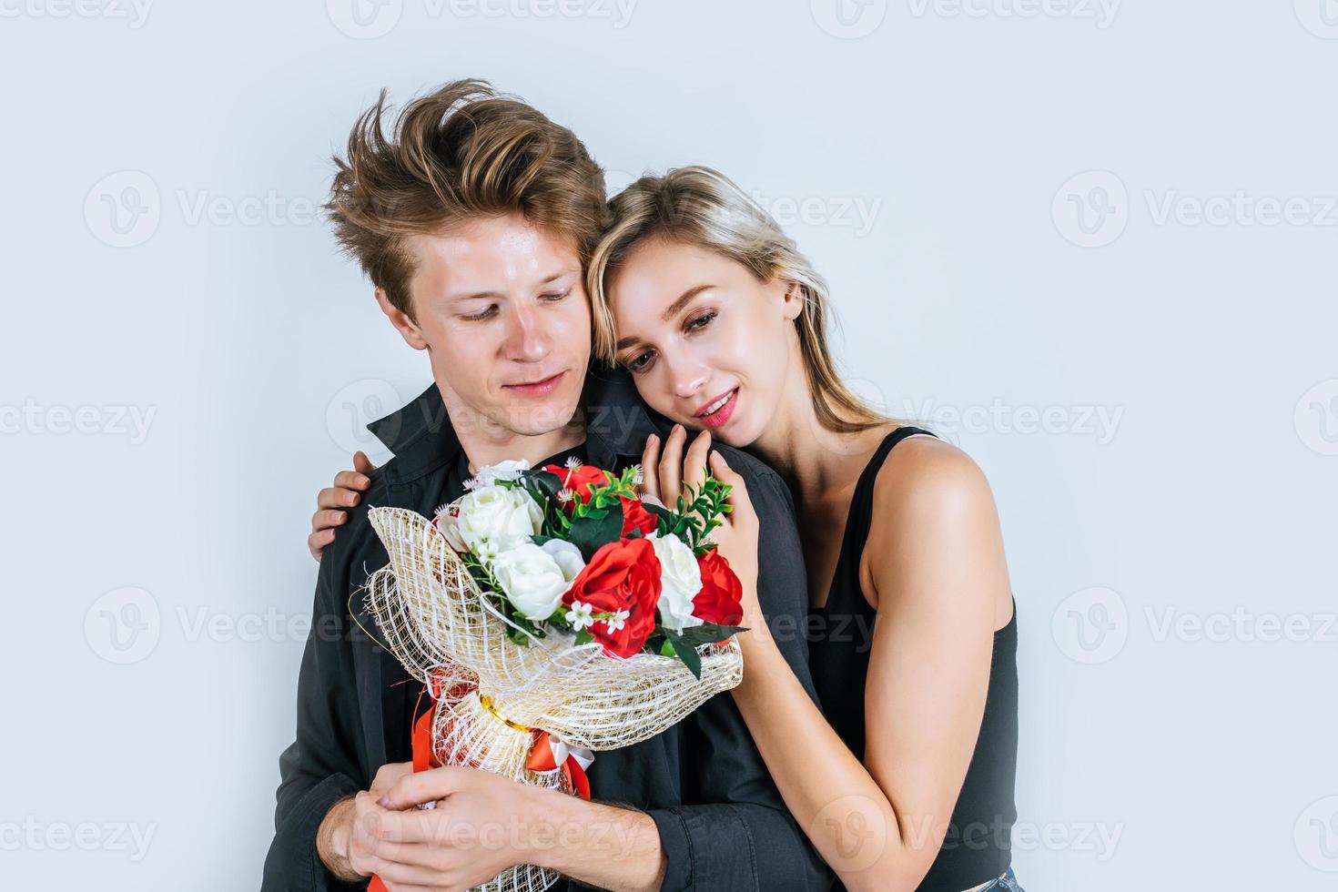 Portrait d'heureux jeune couple avec des fleurs en studio photo