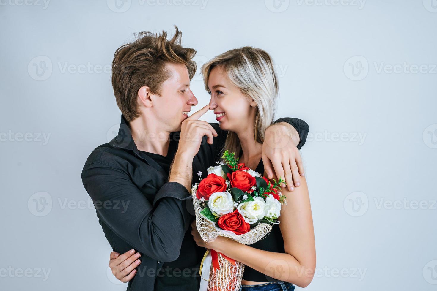 Portrait d'heureux jeune couple avec des fleurs en studio photo