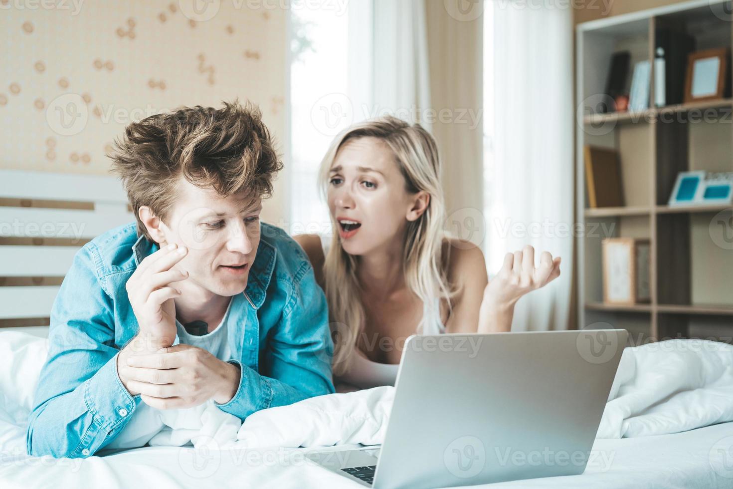 couple heureux utilisant un ordinateur portable sur le lit photo