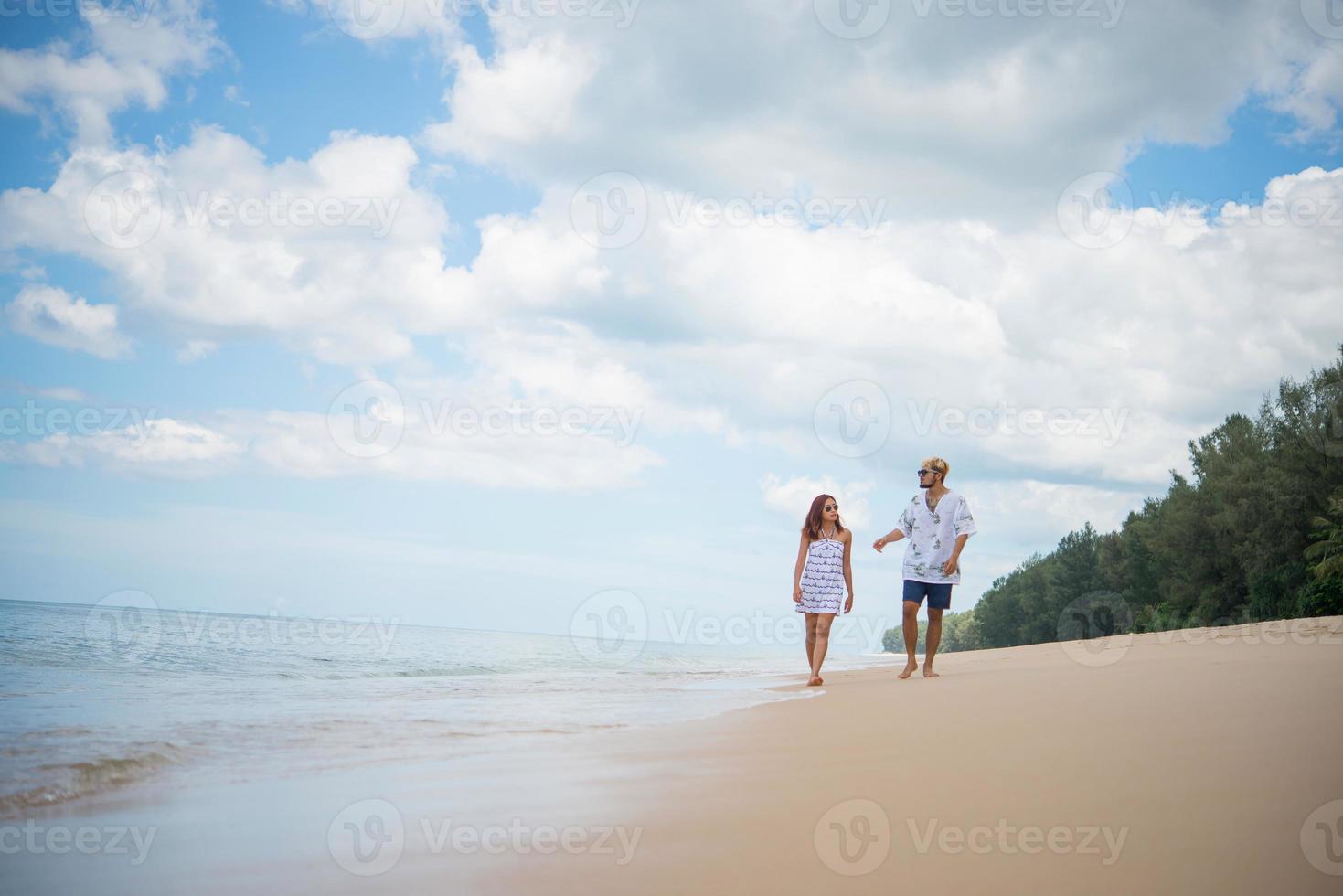 jeune couple heureux marchant sur la plage souriant photo