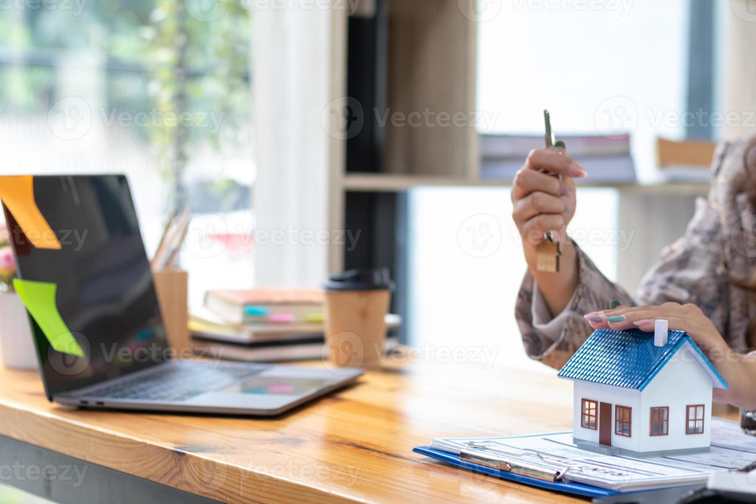 une réel biens agent est en train de préparer à livrer le maison et clés à le client qui signé le achat Contrat à l'intérieur le réel biens bureau. réel biens commerce des idées et avoir livré de agents immobiliers photo