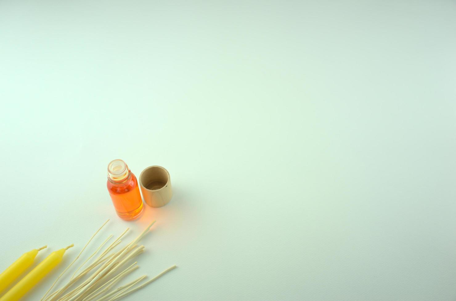 huile parfumée orange dans une bouteille avec des bougies jaunes et des bâtons en bois photo